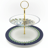 "Elegant two-tiered peacock serving stand with navy blue and white porcelain plates and gold metal stand on white background"
